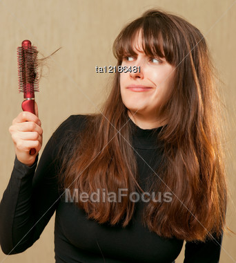 Confused Woman With Tangled Hair Holds A Hairbrush In The Hand Stock Photo