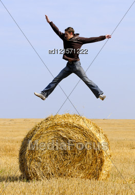 Man Jumping Up On Straw Roll Stock Photo