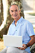 Grey Haired Man In Park With Laptop Computer
